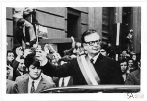 Salvador Allende en auto descapotado con banda presidencial y bandera en la mano, el día de la asunción a la presidencia (1970). Centro de Documentación de la Fundación Salvador Allende.
