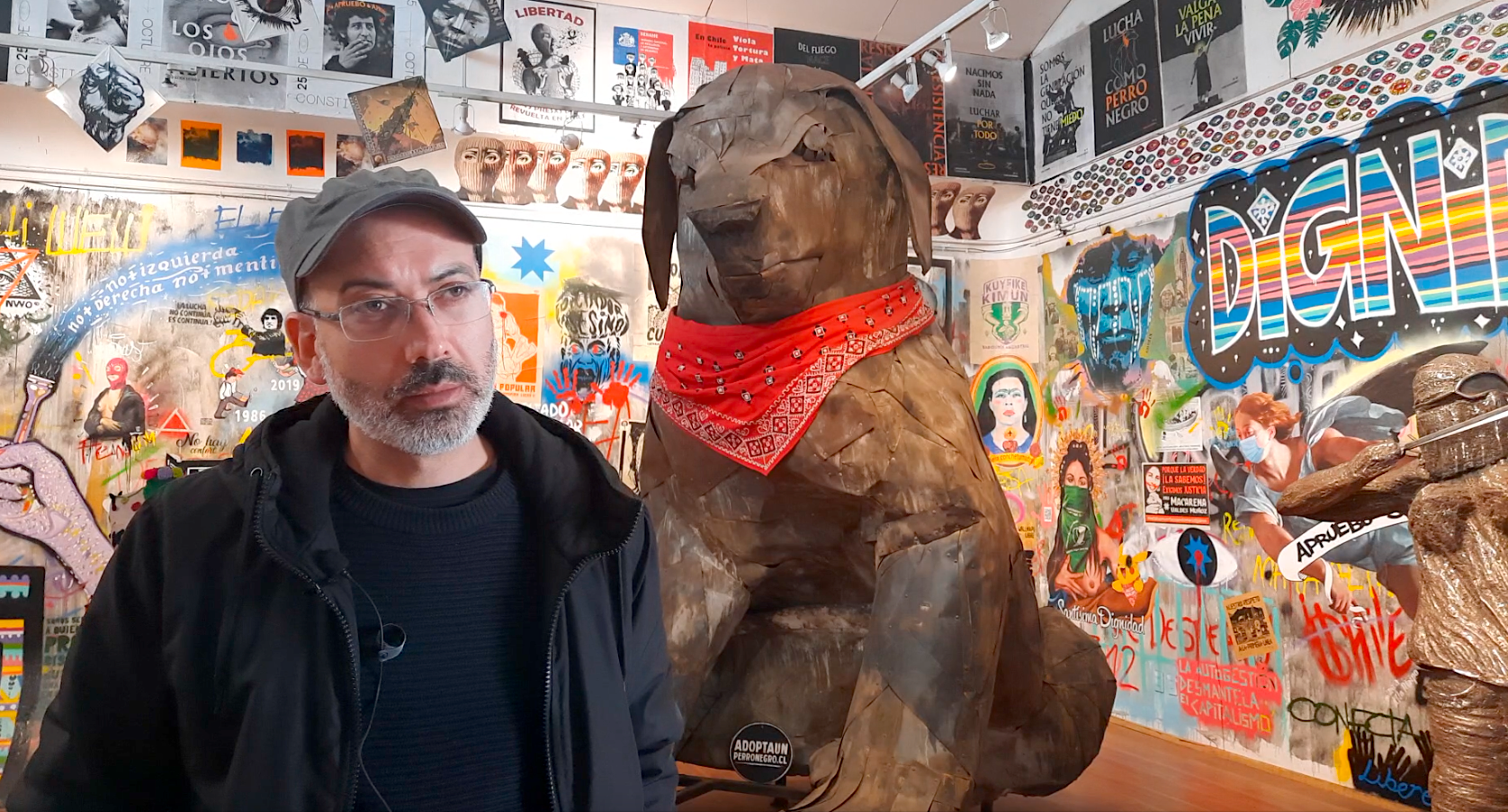 El museólogo y curador del Museo del Estallido, Marcel Solá, posa adelante de su otra gran obra: la escultura del perro Matapacos